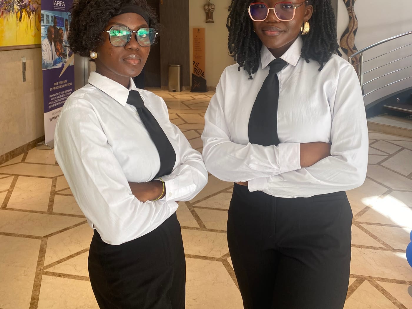 Deux hôtesses Jua Prestige devant la signalétique du Colloque IARPA